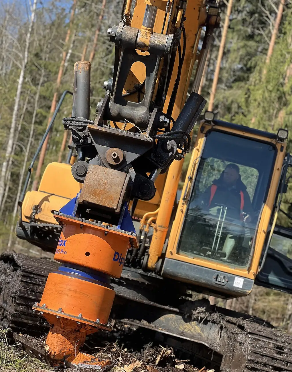 Excavator-mounted stump auger attachment on a cut stump